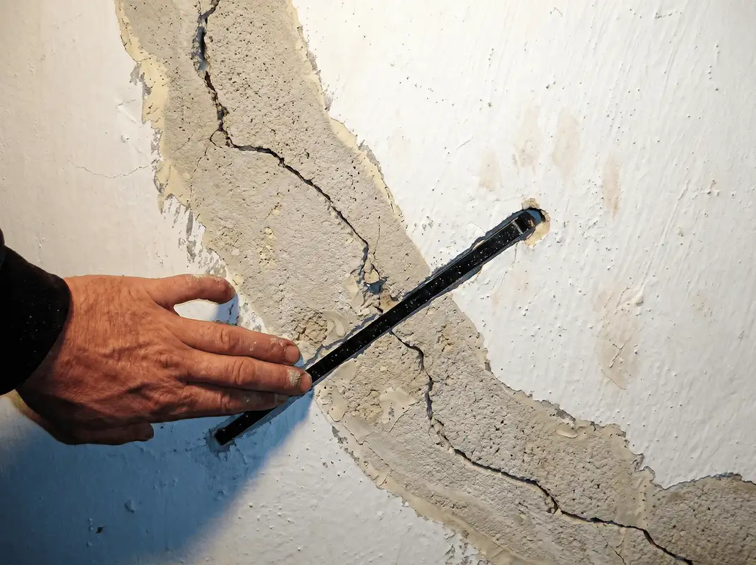 A wall with a large crack is being inspected by a professional in Pasadena, CA